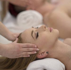 relaxed young couple getting massage in spa